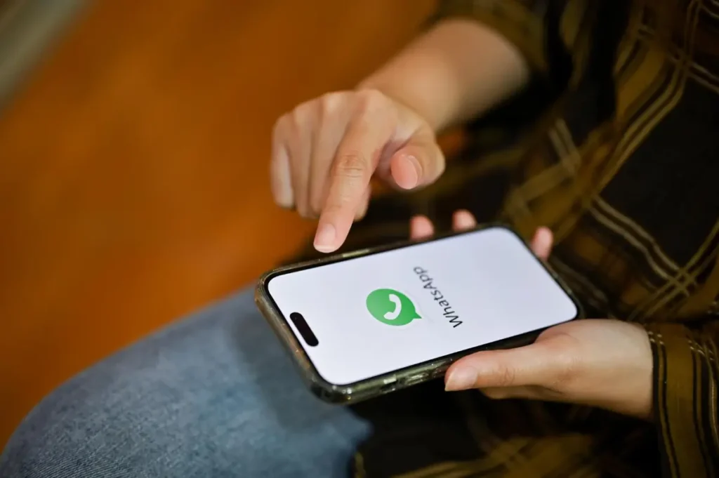 Pessoa abrindo WhatsApp no smartphone, canal de vendas e atendimento para loja de celular